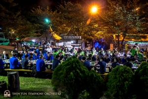 Het herfstweer en de lange gemeenschappelijke tafels zorgden voor een gemoedelijke avond. (Foto door fagottist Steven Louie)