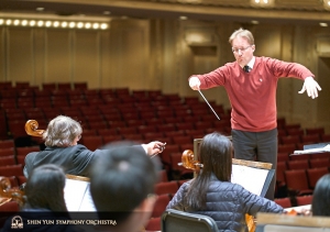 Dirigent Dmitry Russu werkt met de cellosectie.