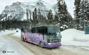 De levendige Shen Yun tourbus van de groep voegt een vleugje kleur toe aan de witte sneeuw en de donkere evergreens.
